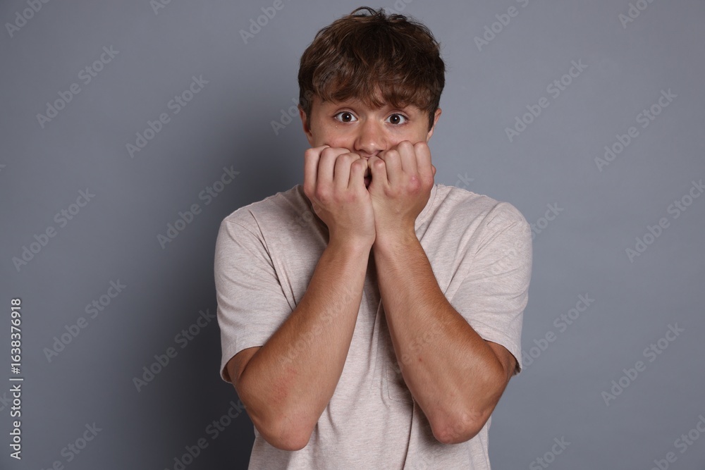 Teenage boy suffering from panic attack on grey background Teenage boy suffering from panic attack on grey background