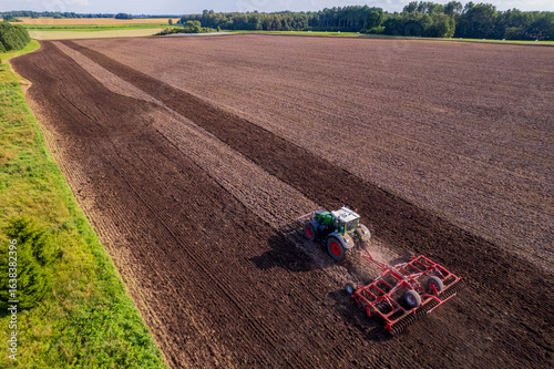 tractor cultivating a field with a harrow