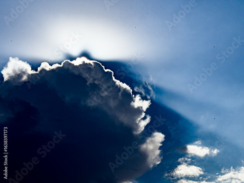 Dramatic Sunlight Behind Dark Cloud in Blue Sky