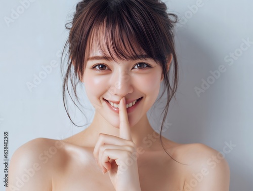 内緒のポーズをする笑顔の美しい女性