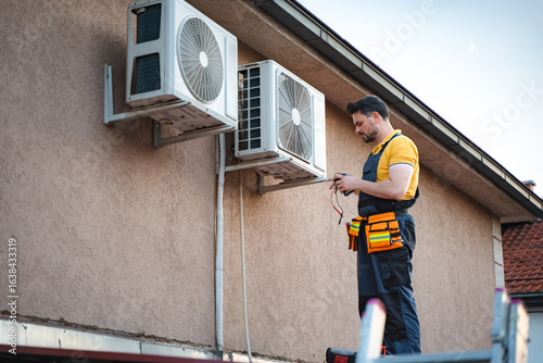Bilde på lerret Technician installing an air conditioner on the wall of a house