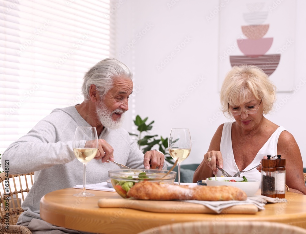 Elderly couple having dinner at table indoors Elderly couple having dinner at table indoors