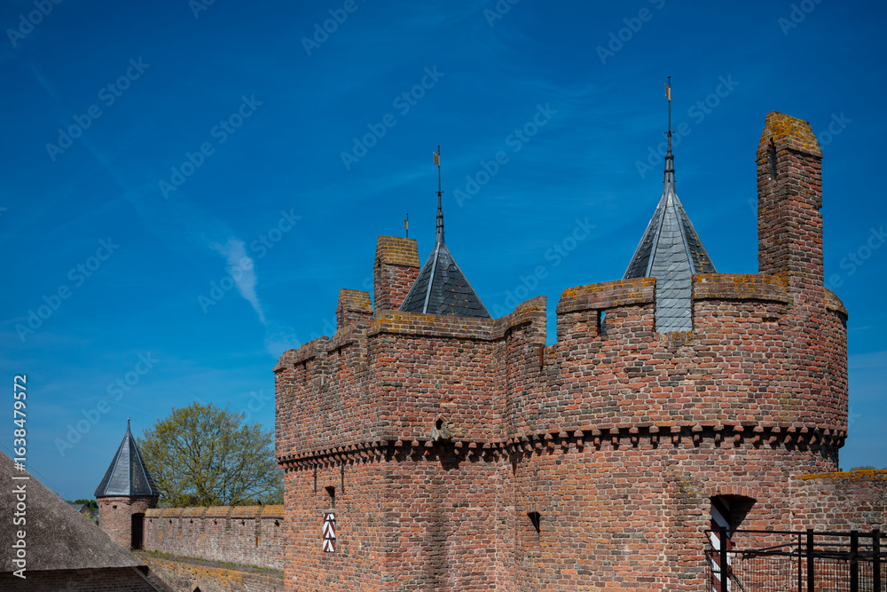 Fototapeta premium Panoramic view of medieval castle complex showing multiple towers and fortification walls against blue sky