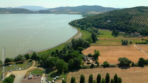 Lake trasimeno coastline showing fields, trees and hills in umbria, italy