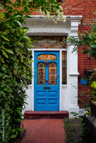 Blue victorian door with stained glass windows surrounded by green plants