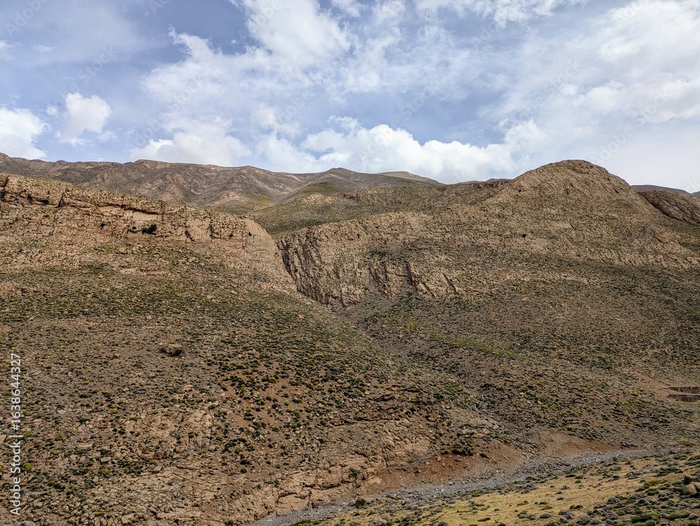 Mountainous terrain with rugged cliffs under a bright sky in Atlas Mountains Mountainous terrain with rugged cliffs under a bright sky in Atlas Mountains