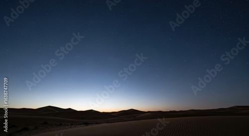 A serene twilight landscape showcases rolling desert dunes under a gradient blue sky.