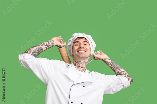 Smiling young chef on green...