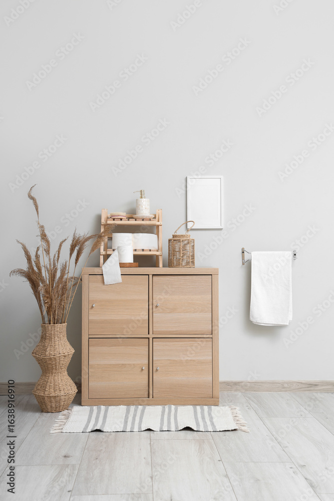 Fototapeta premium Interior of stylish restroom with wooden cabinet, towel and rolls of toilet paper