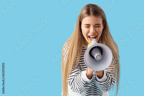 Carta da parati Young woman shouting into megaphone on blue background