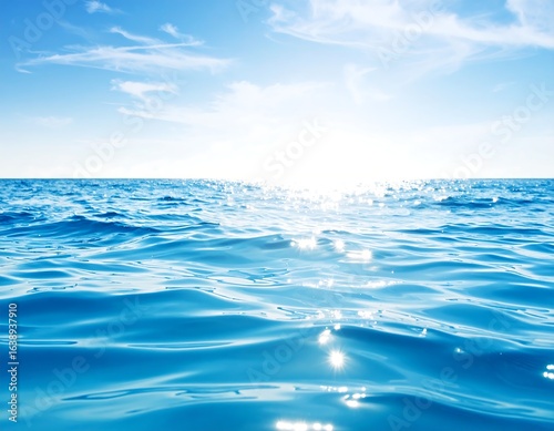 Sunlit ocean surface with gentle waves and a clear blue sky
