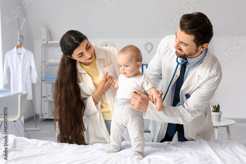 Pediatric healthcare and baby checkup, doctor examining infant with mother in...