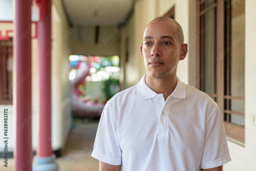 Obraz premium Stylish man in white polo shirt posing in tranquil Zen garden portrait