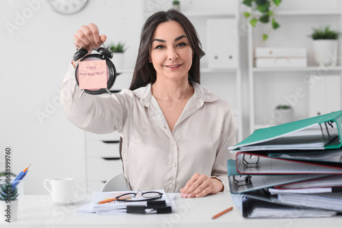 Businesswoman holding alarm...