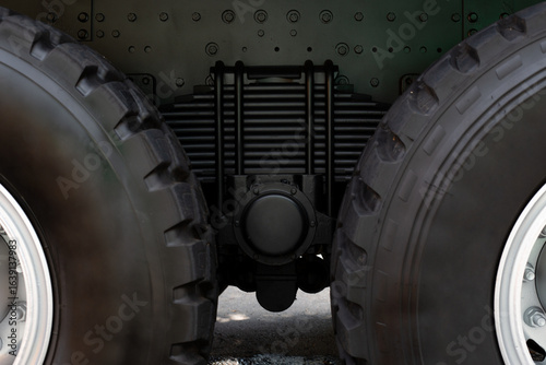 Photos Close up view of the rear axle and suspension system of large vehicle, showcasing the rugged tires and mechanical parts