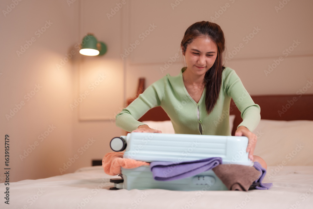 Asian adult woman struggles overpack suitcase prepare travel vacation journey hotel bedroom packing clothes trip holiday Asian adult woman struggles overpack suitcase prepare travel vacation journey hotel bedroom packing clothes trip holiday