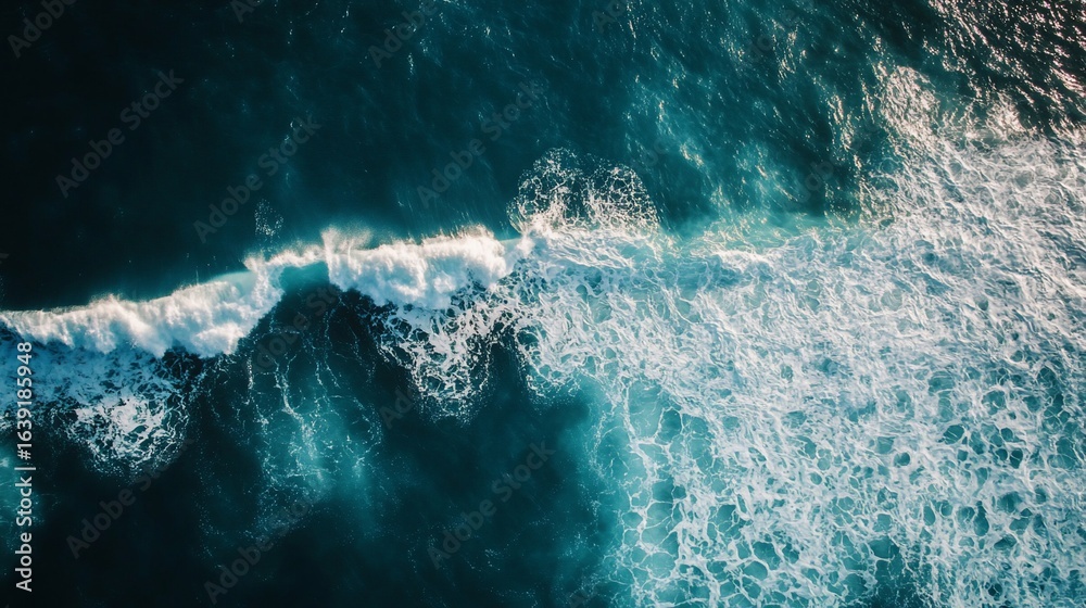 Obraz premium Aerial view of ocean waves displaying turquoise water and foamy texture
