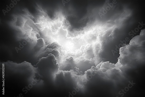 Dramatic black and white clouds swirling around a bright sun breaking through with radiant light beams