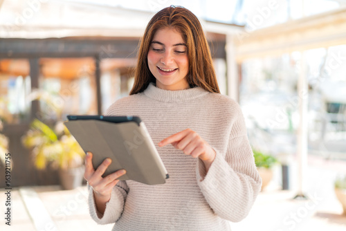 Free Download Young pretty caucasian woman touching the tablet screen with happy expression - GFXLoad