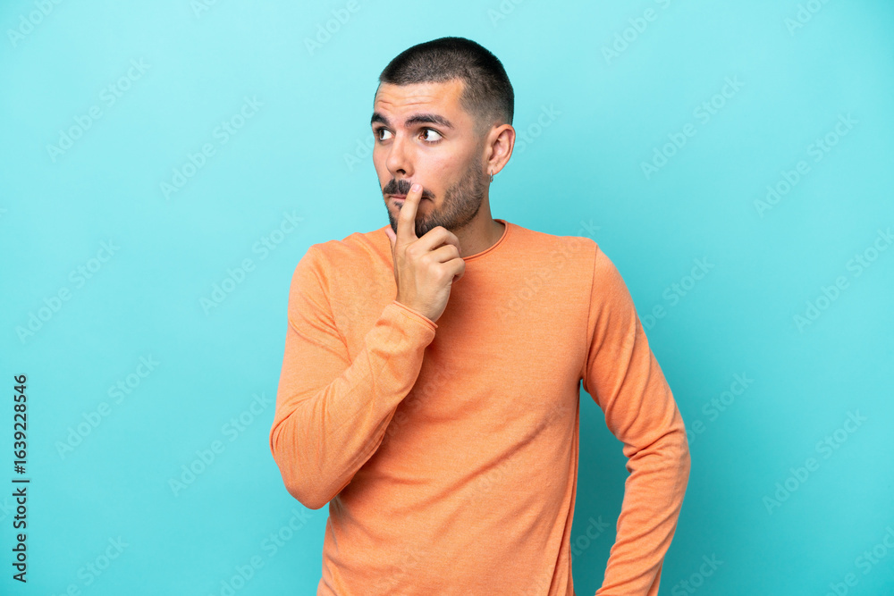Young caucasian man isolated on blue background having doubts and thinking Young caucasian man isolated on blue background having doubts and thinking
