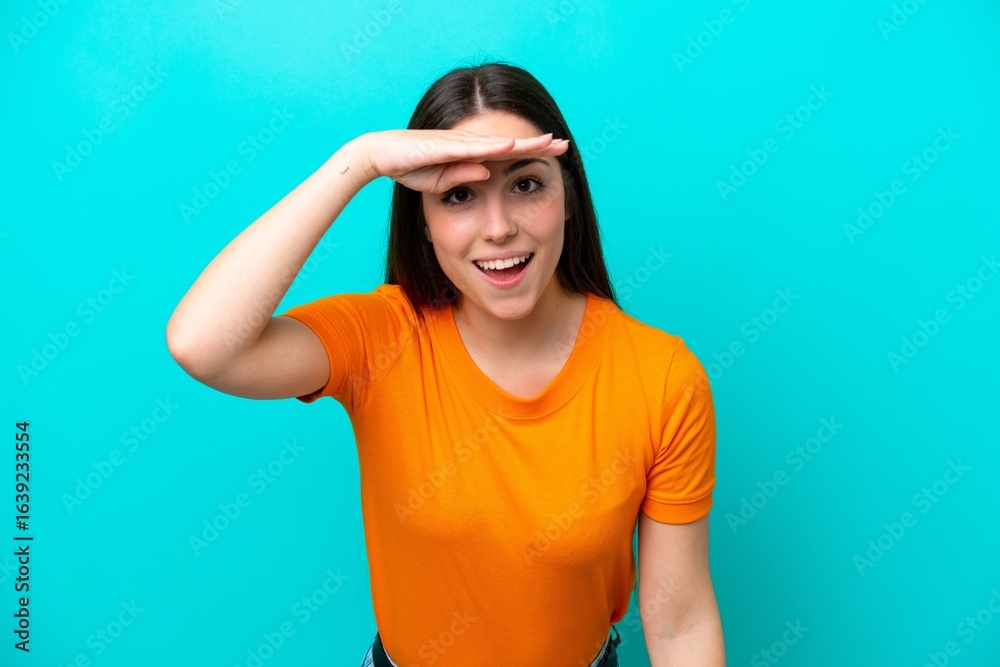 Fototapeta premium Young caucasian woman isolated on blue background looking far away with hand to look something