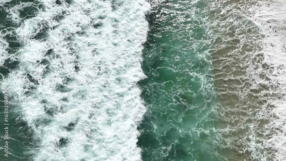 Giant ocean waves crashing and foaming on empty sand tropical beach with big rock stones Giant ocean waves crashing and foaming on empty sand tropical beach with big rock stones