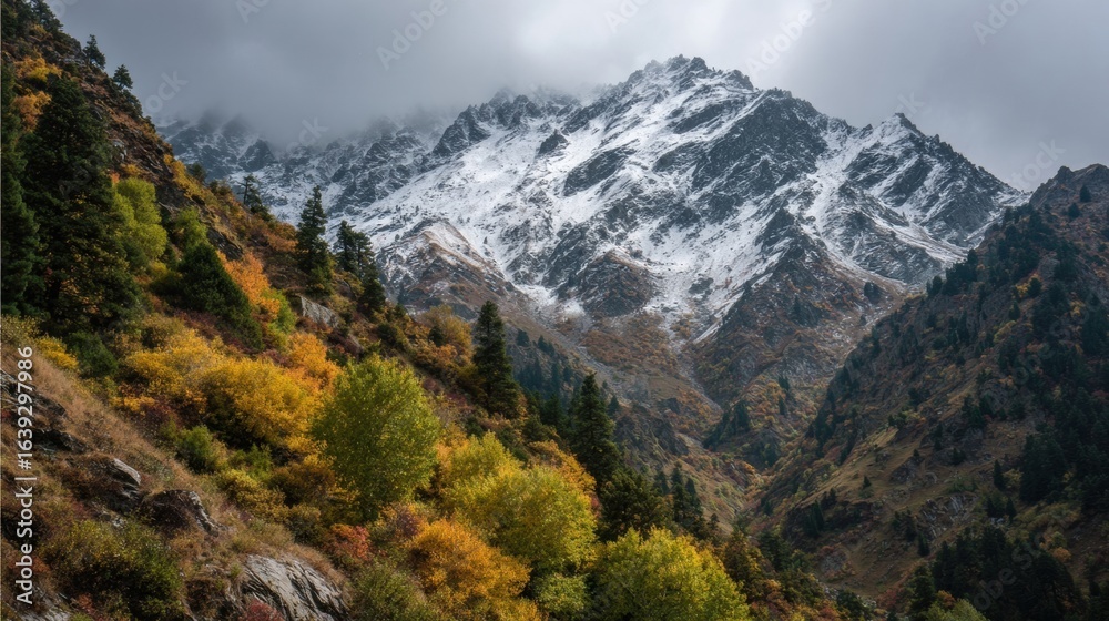 Fototapeta premium Spectacular Autumn Landscape Showcasing Snow-Capped Mountains and Vibrant Foliage Under a Cloudy Sky
