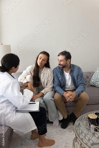 Fotografie Married couple getting professional advice, receiving counselling support from female psychologist or medical specialist during visit in clinic