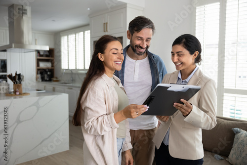 Photos Couple reviewing mortgage or real estate documents during meeting with Indian wo