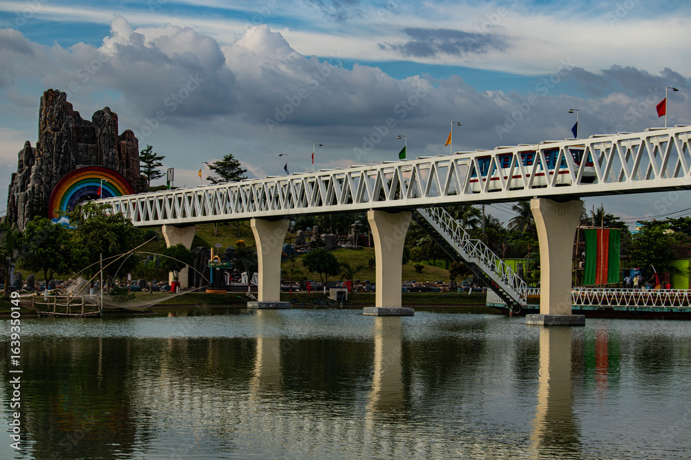 Obraz premium Mini park train riding on a small decorative bridge.