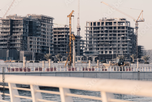 Construction site of modern residential buildings with cranes and industrial machines, Abu Dhabi