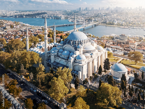 Big ancient mosque with four minarets in front of modern cityscape on sunny day, Istanbul, Türkiye
