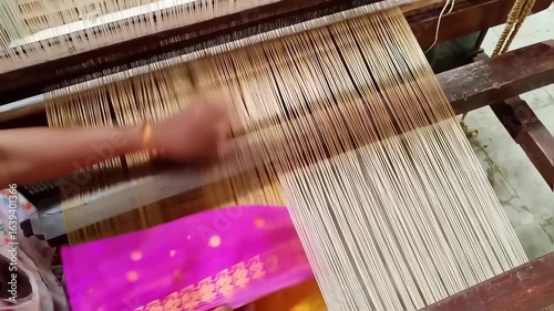 Hands working on a loom, creating a colorful fabric