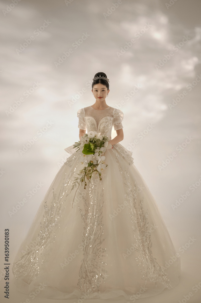 Elegant female model in wedding gown holding bouquet. Elegant female model in wedding gown holding bouquet.