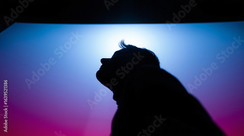 Silhouette of a person standing against a vibrant, colorful gradient background.