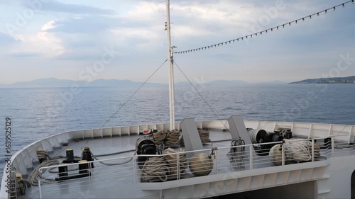 Wallpaper Mural Evening view from the bow of a large ferry crossing the Saronic Gulf from Aegina to Athens. Thick ropes, bollards, and deck gear in the foreground, mast with cables and lights, calm open sea Torontodigital.ca