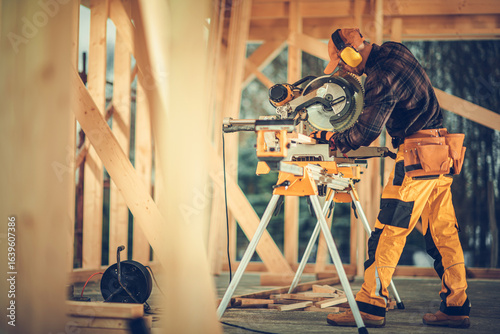 Foto Skilled Carpenter Working With a Miter Saw in a Wooden Construction Site