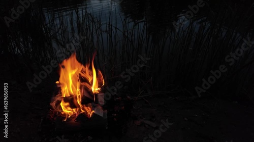 a burning fire after sunset against the backdrop of a calm river