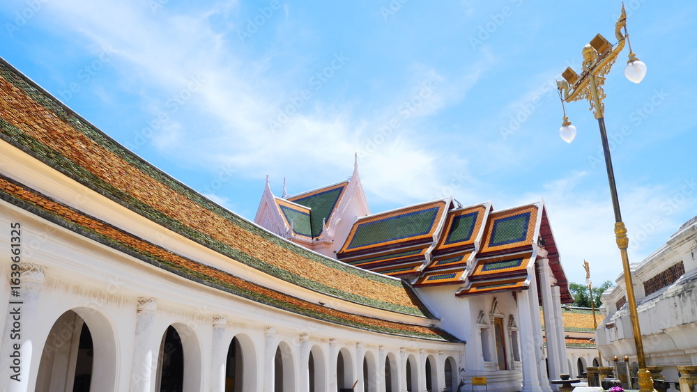 Obraz premium Beautiful temple architecture with arched walkway and traditional tiled roof in Thailand
