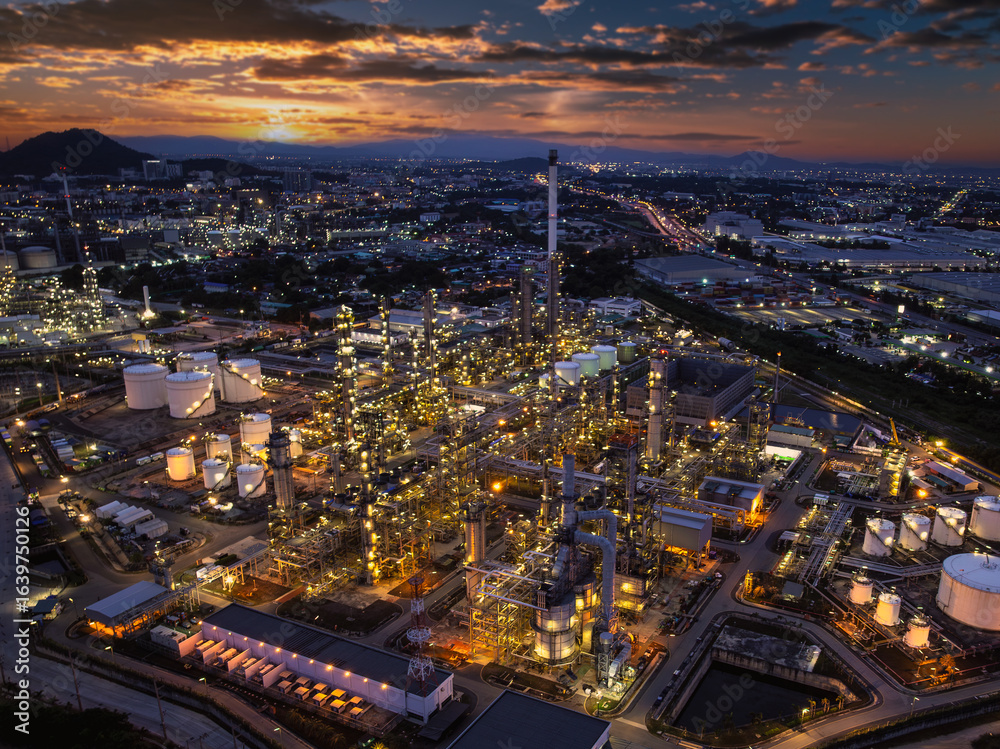 Obraz premium Oil refinery plant industry factory zone, oil and gas petrochemical industrial, oil storage tank and pipeline steel, twilight scene and over lighting equipment and the sunset and cloud sky background,