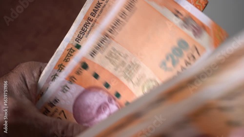 Close up hand of Indian Man Counting 200 Rupee Currency Notes