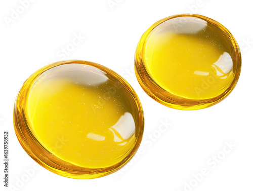Two glossy, amber-yellow, round objects, resembling capsules or gems, with a transparent, slightly reflective surface