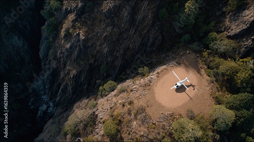white helicopter lands on  remote helipad located on  rugged mountain plateau next to  steep canyon surrounded by trees