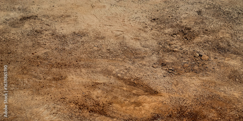 a patch of brown, loose soil. a mix of sand, silt, and clay. baseball field with use and some prints. abstract ground or barren earth background banner with copy space.