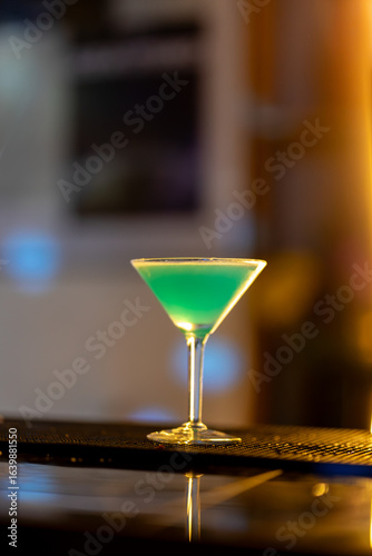 Wallpaper Mural Turquoise cocktail resting on sleek bar counter, warm golden lighting highlighting drink's vivid color and elegant bar atmosphere Torontodigital.ca