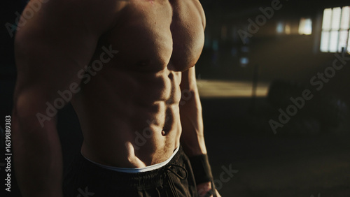 Schilderij op canvas Bodybuilder showing his six pack in a dark gym