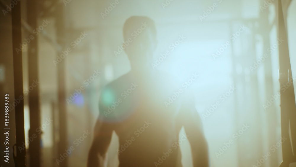 Muscular athlete walking in smoky gym after intense workout Muscular athlete walking in smoky gym after intense workout