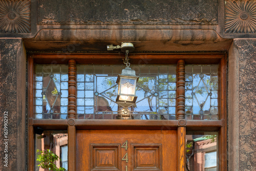 Details of a classic doorway with geometric transom window and glowing lantern light in Boston, Massachusetts, USA
