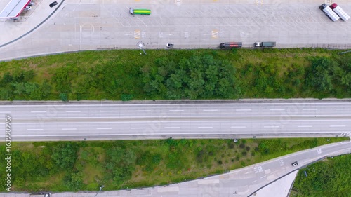 Aerial Drone View of Highway and Cars Driving Through Green Fields and Forest, with Vast Summer Landscape, Blue Sky, and Clouds for a Healing Scenery