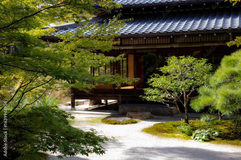 A traditional Japanese building on an elevated wooden platform, overlooking a serene Zen garden with raked gravel and moss. A traditional Japanese building on an elevated wooden platform, overlooking a serene Zen garden with raked gravel and moss.
